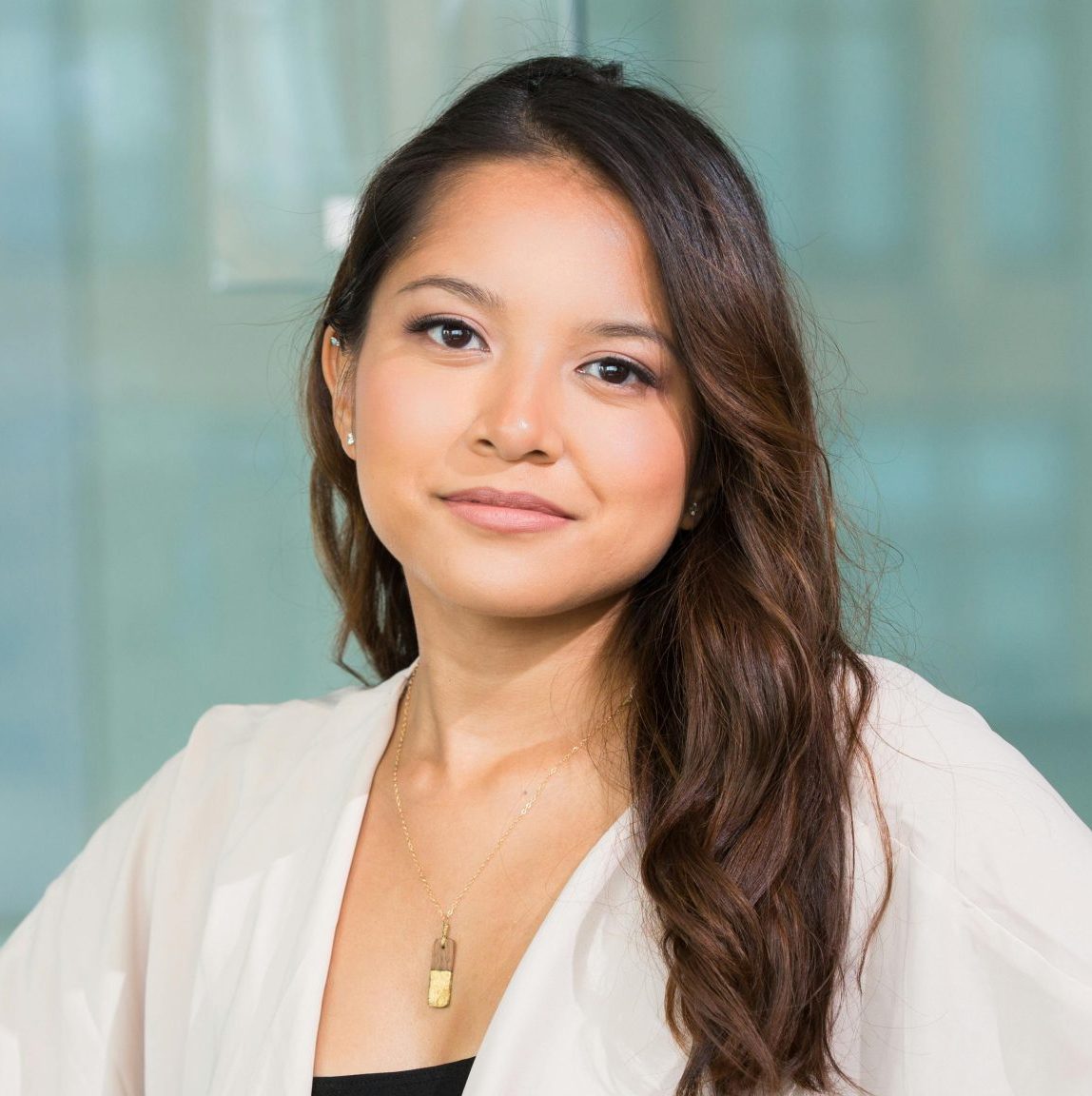 A professional Asian businesswoman sitting confidently in a modern office setting.
