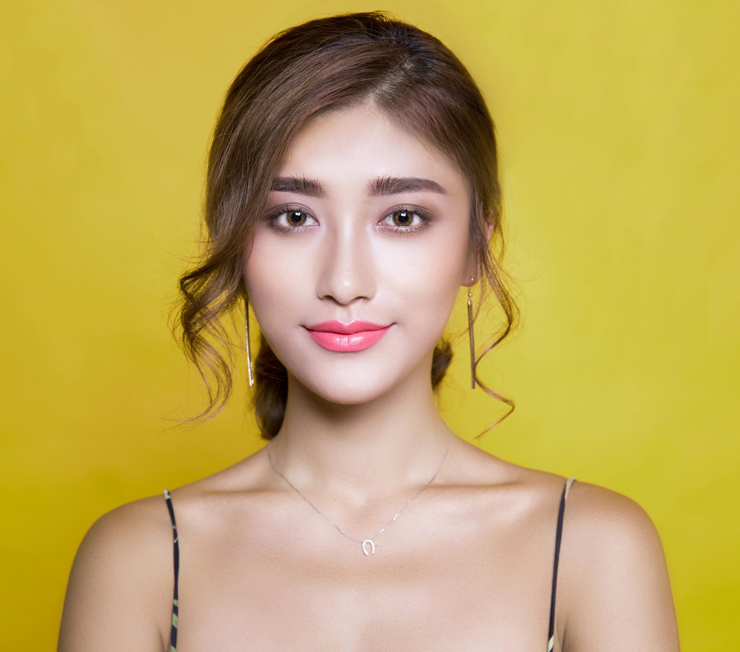 Beautiful portrait of a woman with elegant hairstyle on a vibrant yellow background.